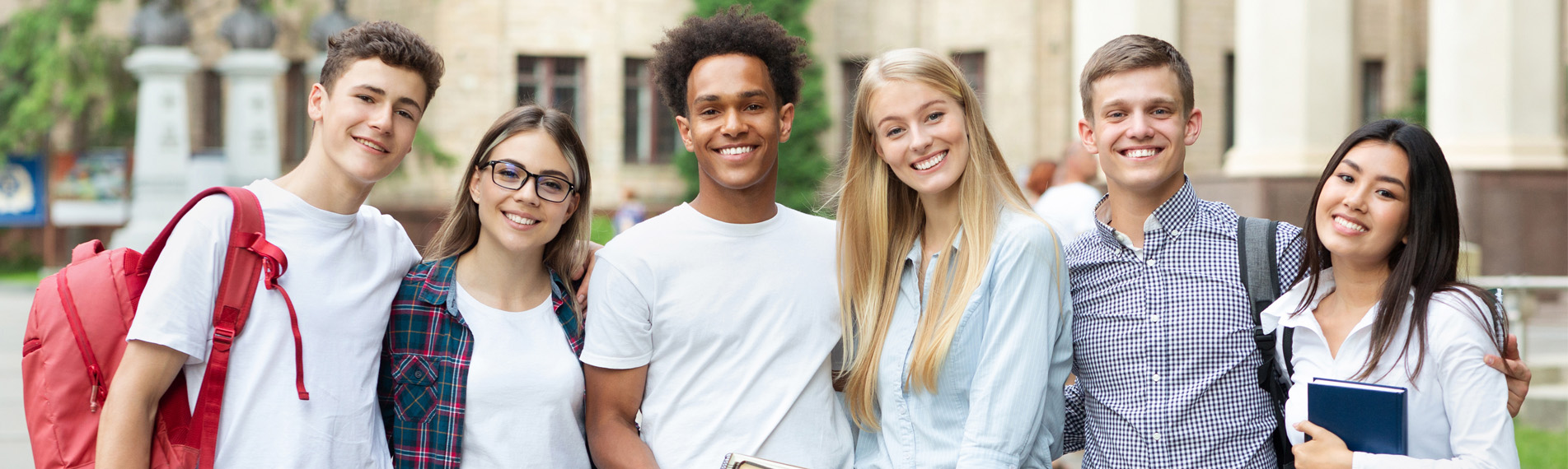 A group of diverse students on campus, posing in front of university